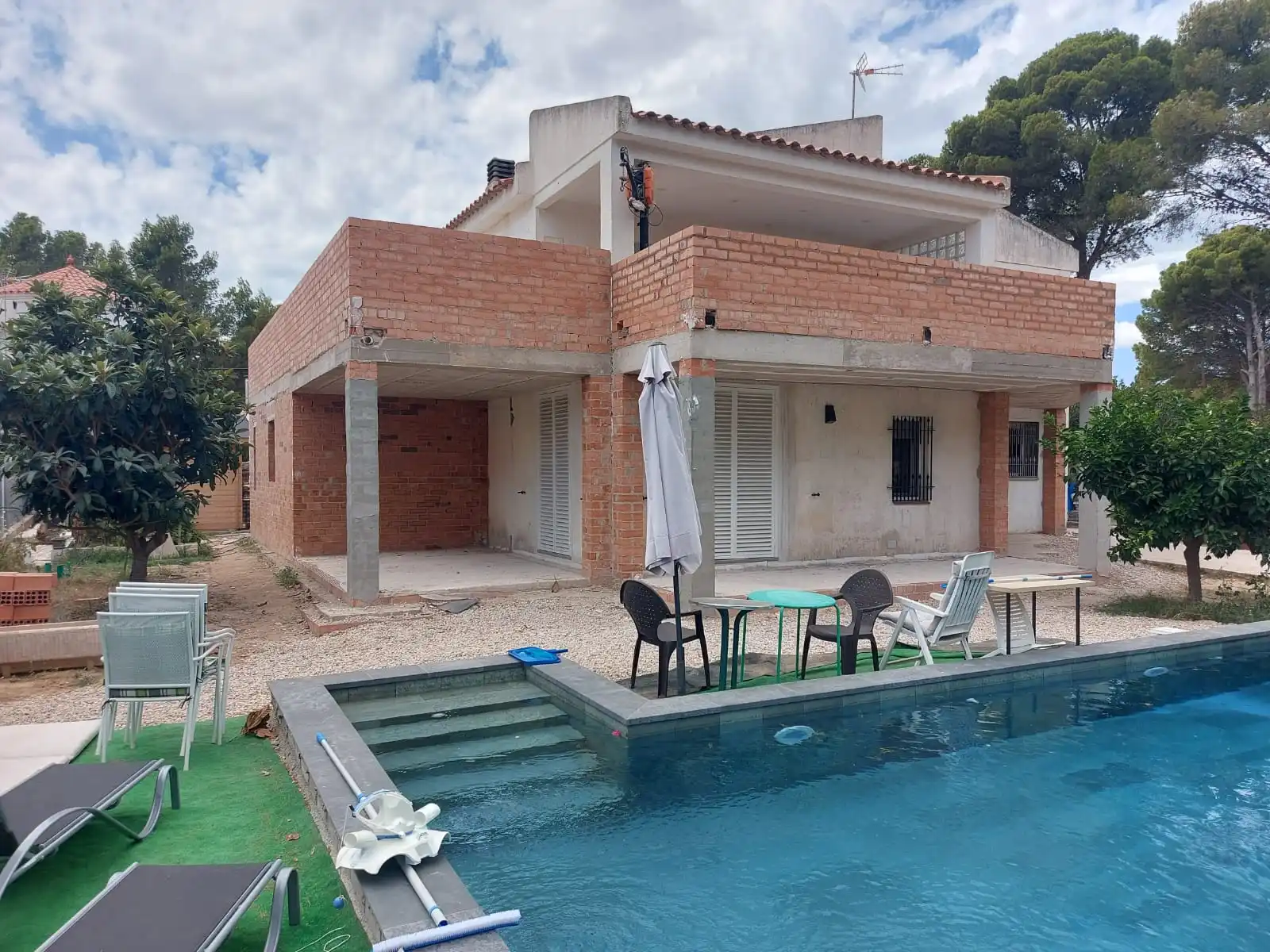 Construcción de ampliación de vivienda con estructura de ladrillo visto junto a piscina en Tarragona