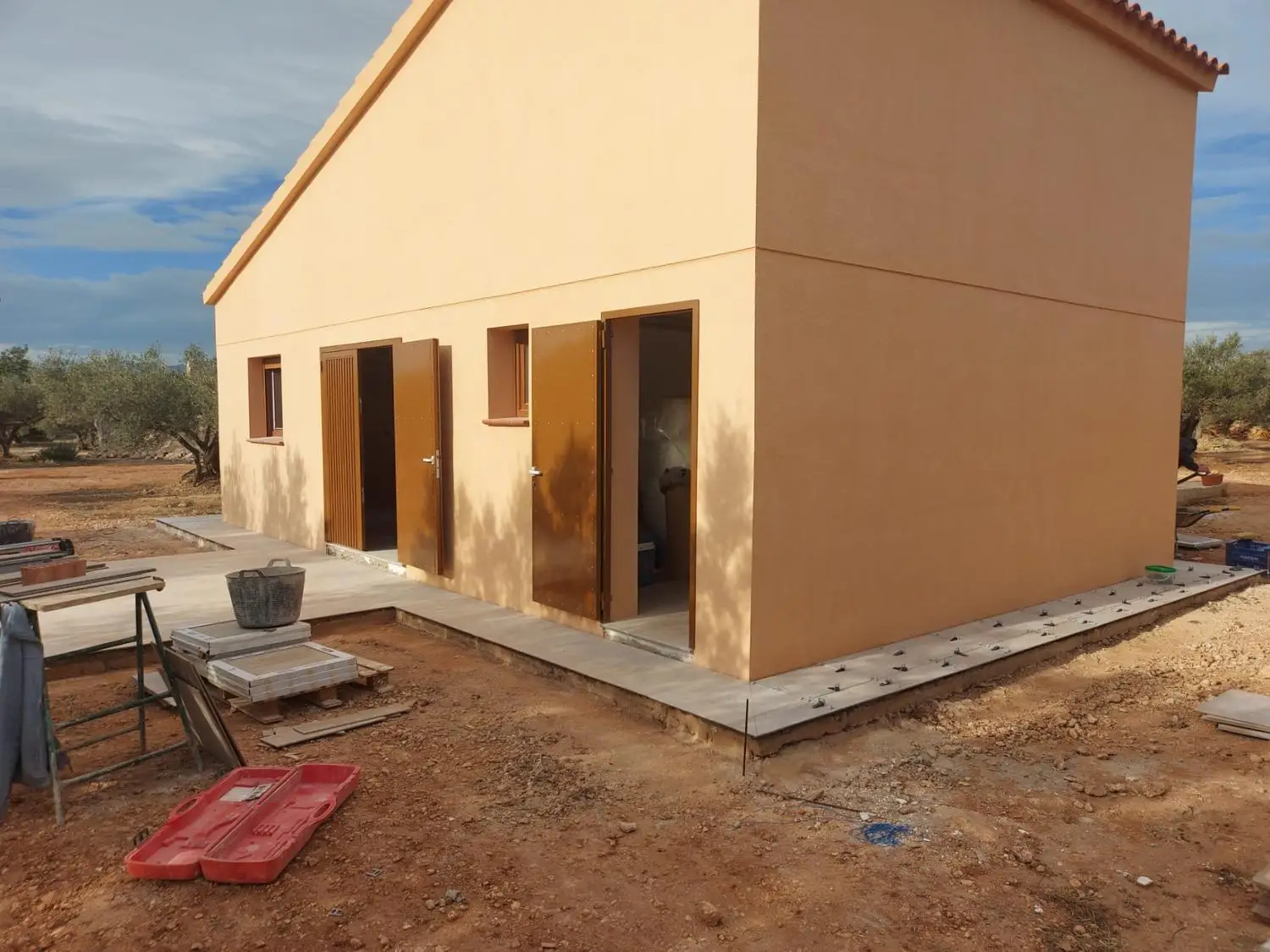 Construcción de vivienda unifamiliar con fachada de mortero monocapa ocre y carpintería metálica en Tarragona