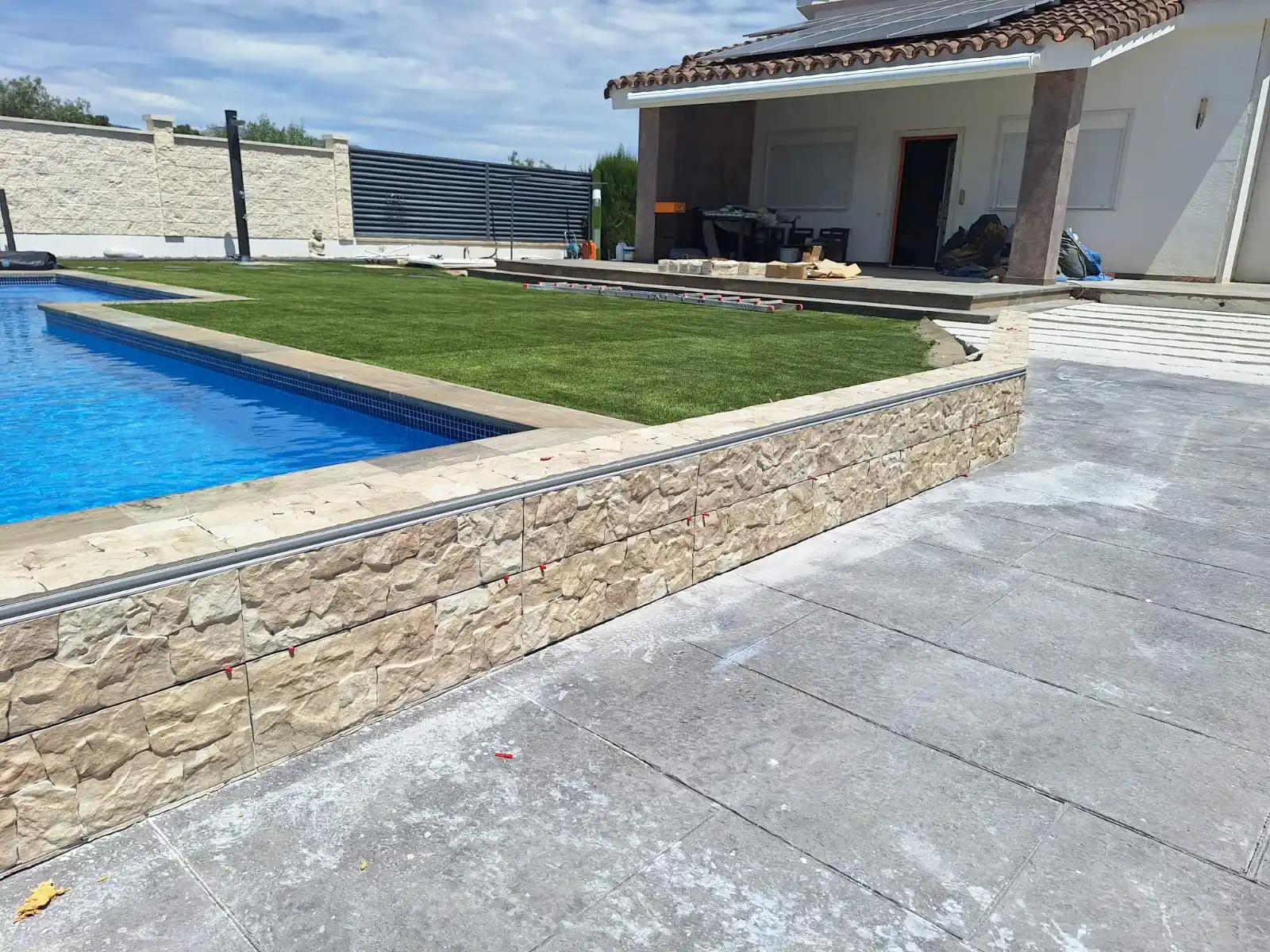 Construcción de muro de piedra decorativa junto a piscina y zona de césped en Tarragona
