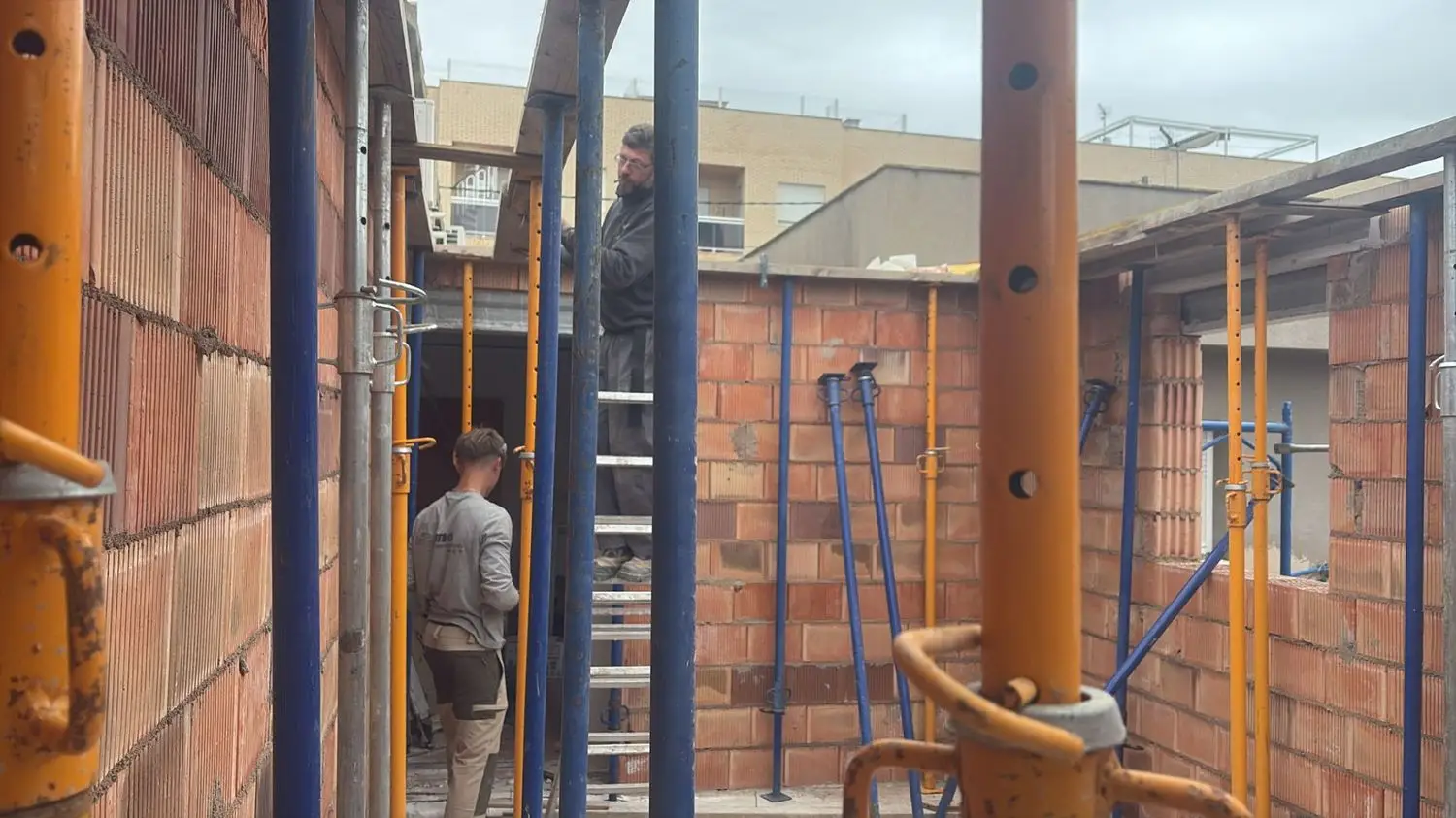 Construcción de muros de ladrillo con operarios y puntales metálicos de soporte en Tarragona