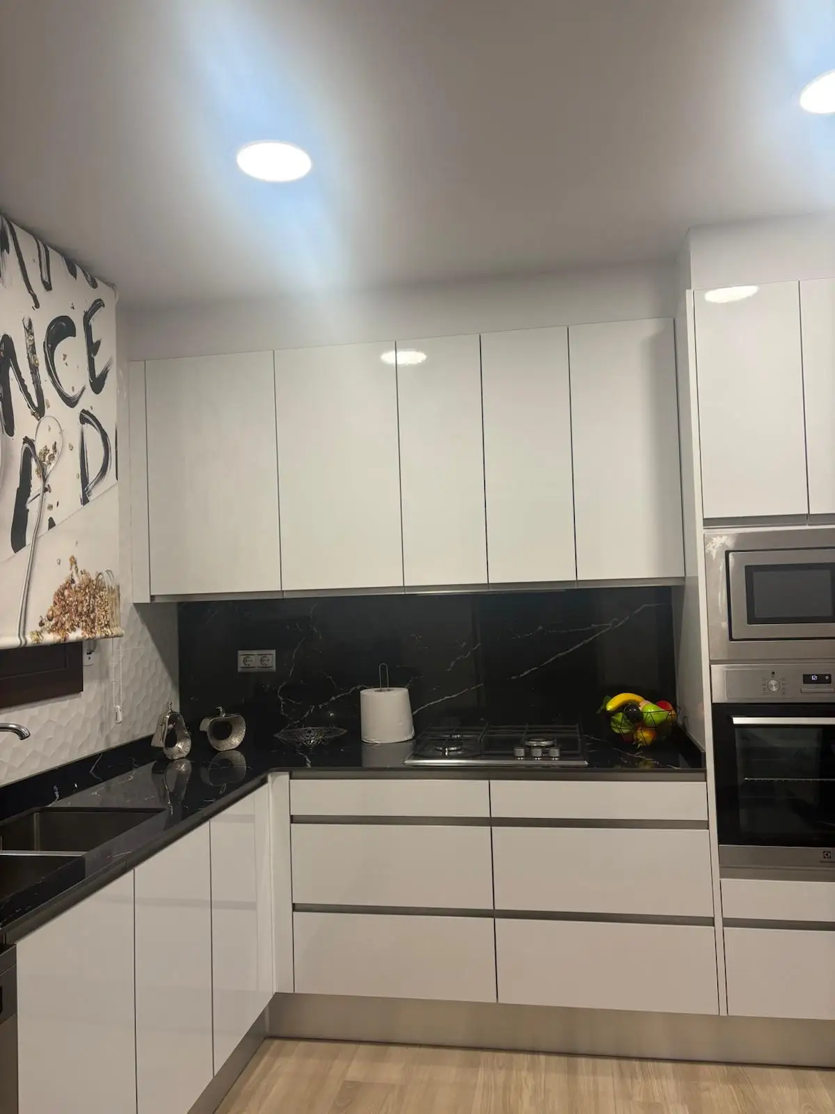 Reforma de cocina con armarios blancos sin tiradores y encimera de granito negro en Tarragona