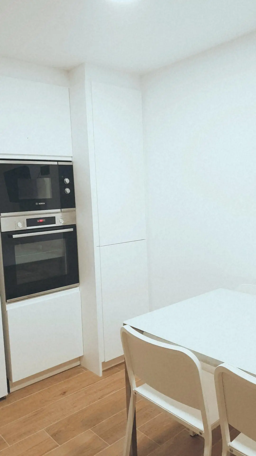 Reforma cocina con mobiliario blanco minimalista, electrodomésticos integrados y suelo de gres cerámico en Tarragona