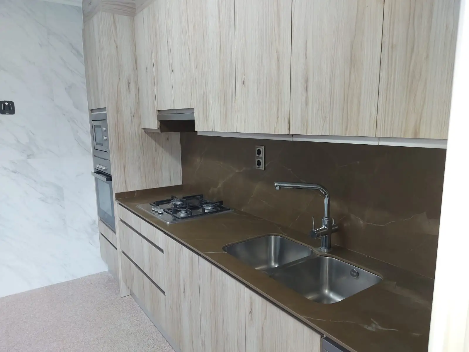 Reforma de cocina con armarios de madera clara y encimera marrón de piedra en Tarragona