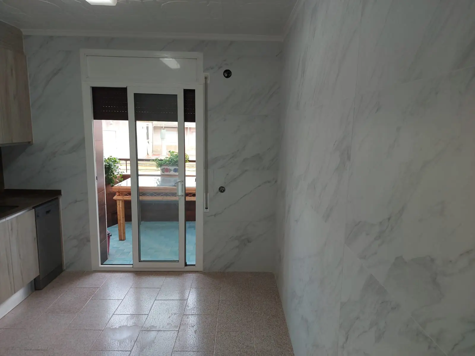 Reforma de cocina con paredes de gres cerámico efecto mármol y salida a terraza en Tarragona
