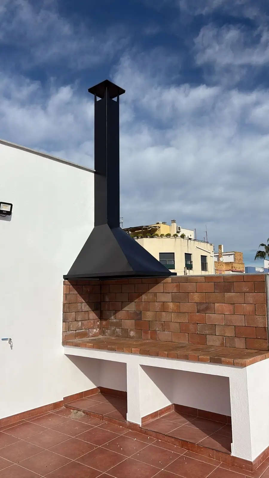 Construcción de barbacoa de obra con ladrillo visto y campana metálica negra en Tarragona