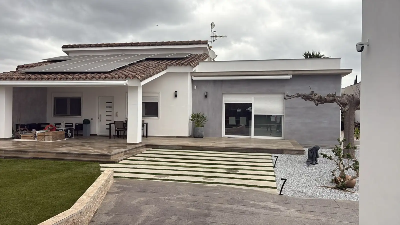Instalación de paneles solares sobre tejado de teja en vivienda con fachada gris en Tarragona