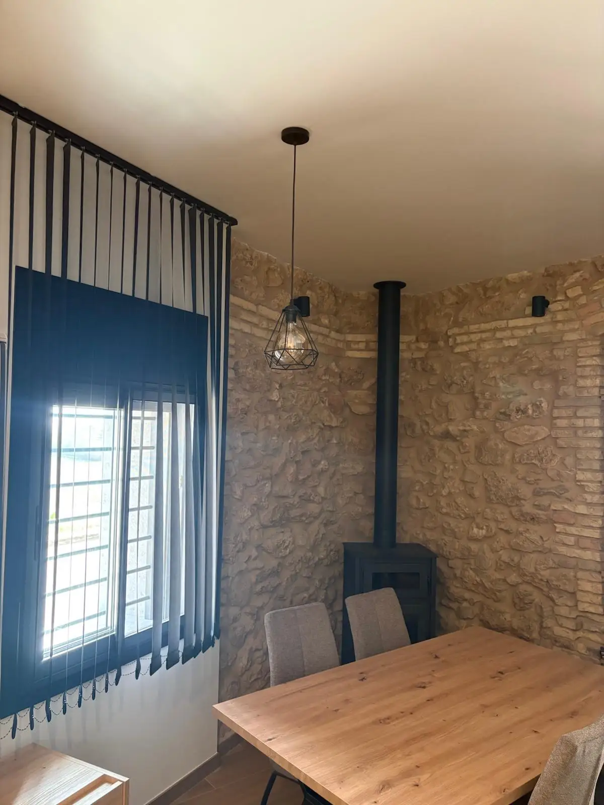 Reforma integral con pared de piedra natural vista y chimenea de hierro negra en Tarragona