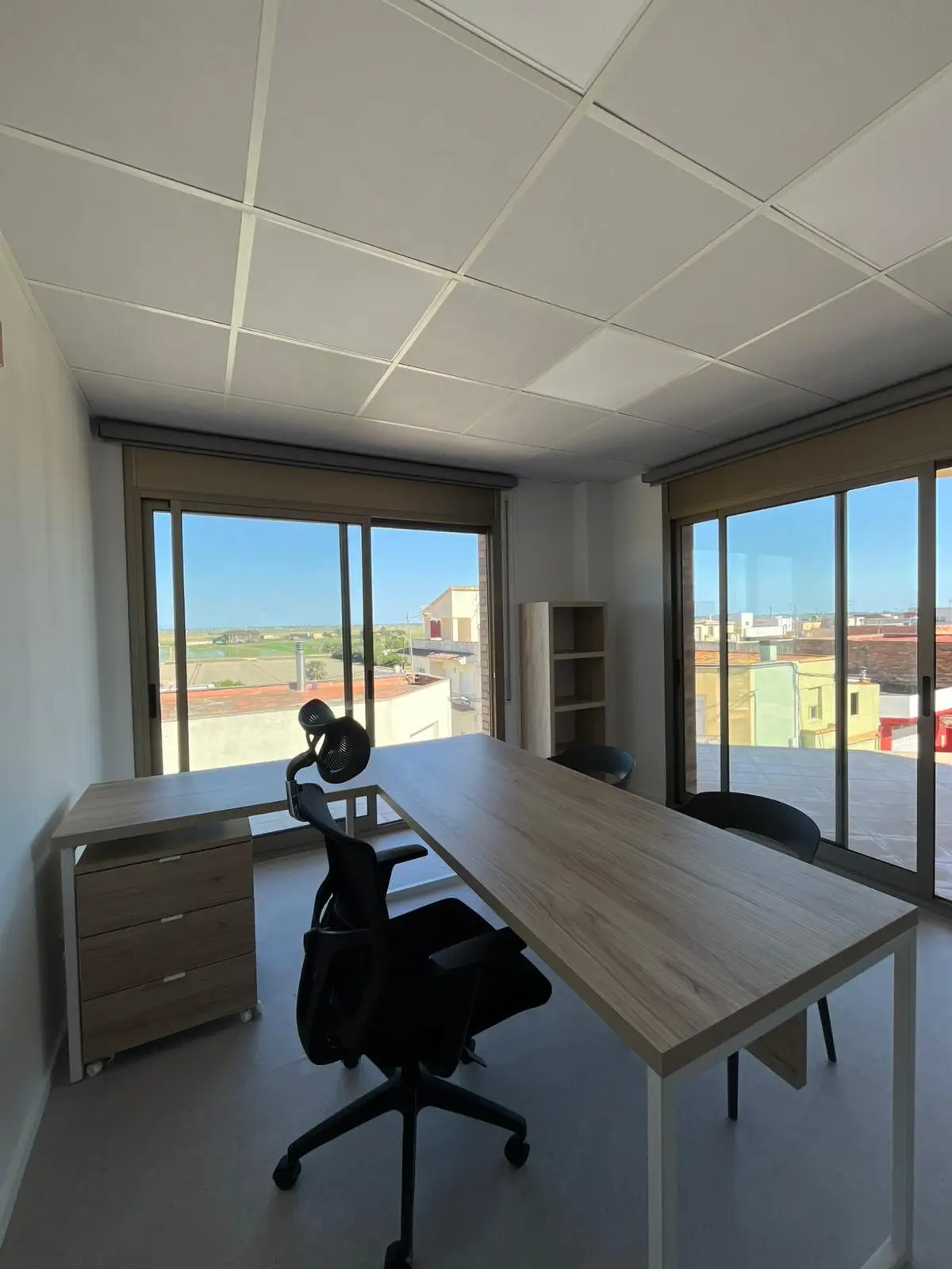 Reforma integral de oficina con techo técnico de placas blancas y mobiliario de madera en Tarragona
