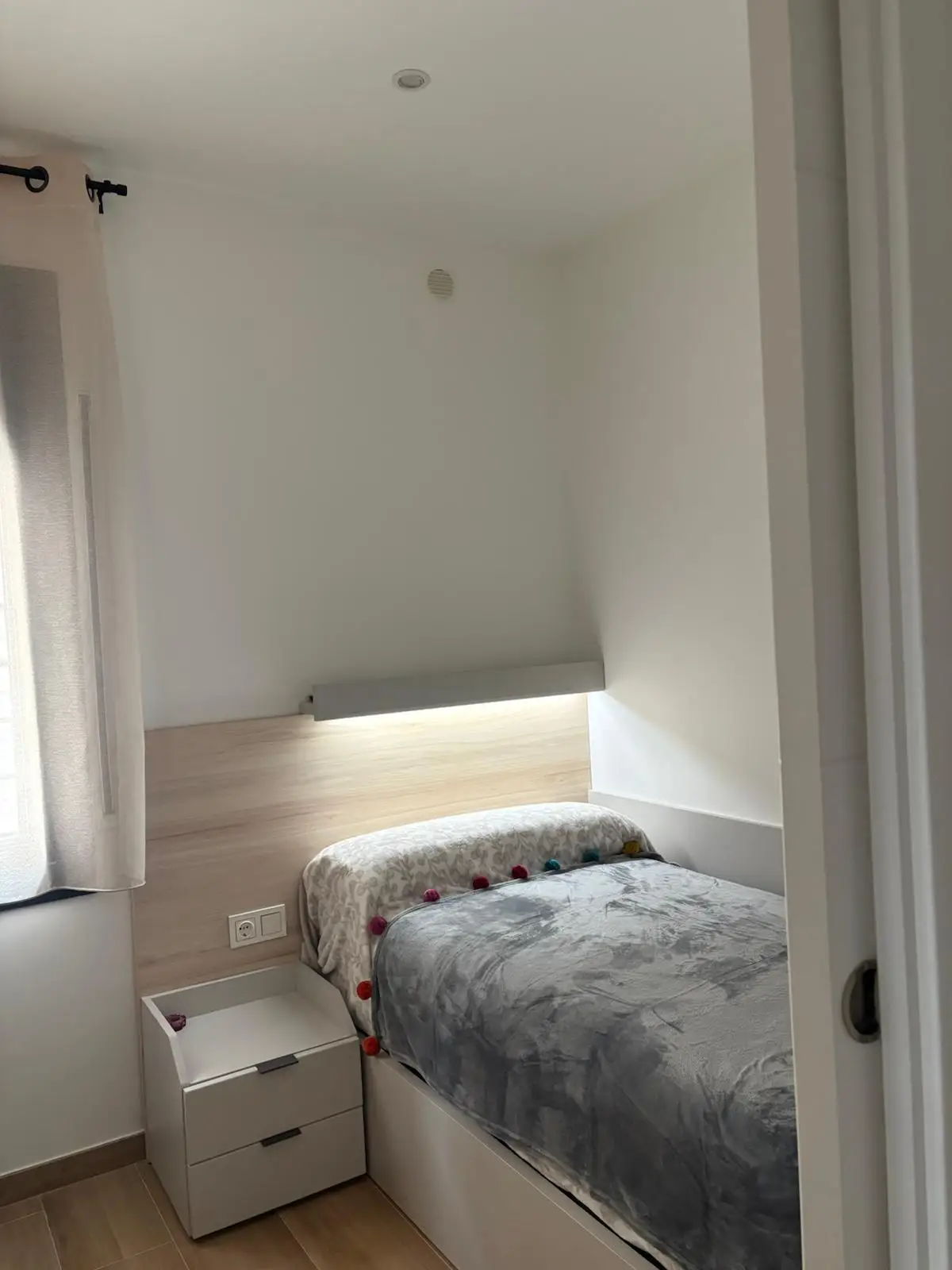 Reforma de vivienda con dormitorio juvenil que incluye cabecero de madera y luz LED en Tarragona