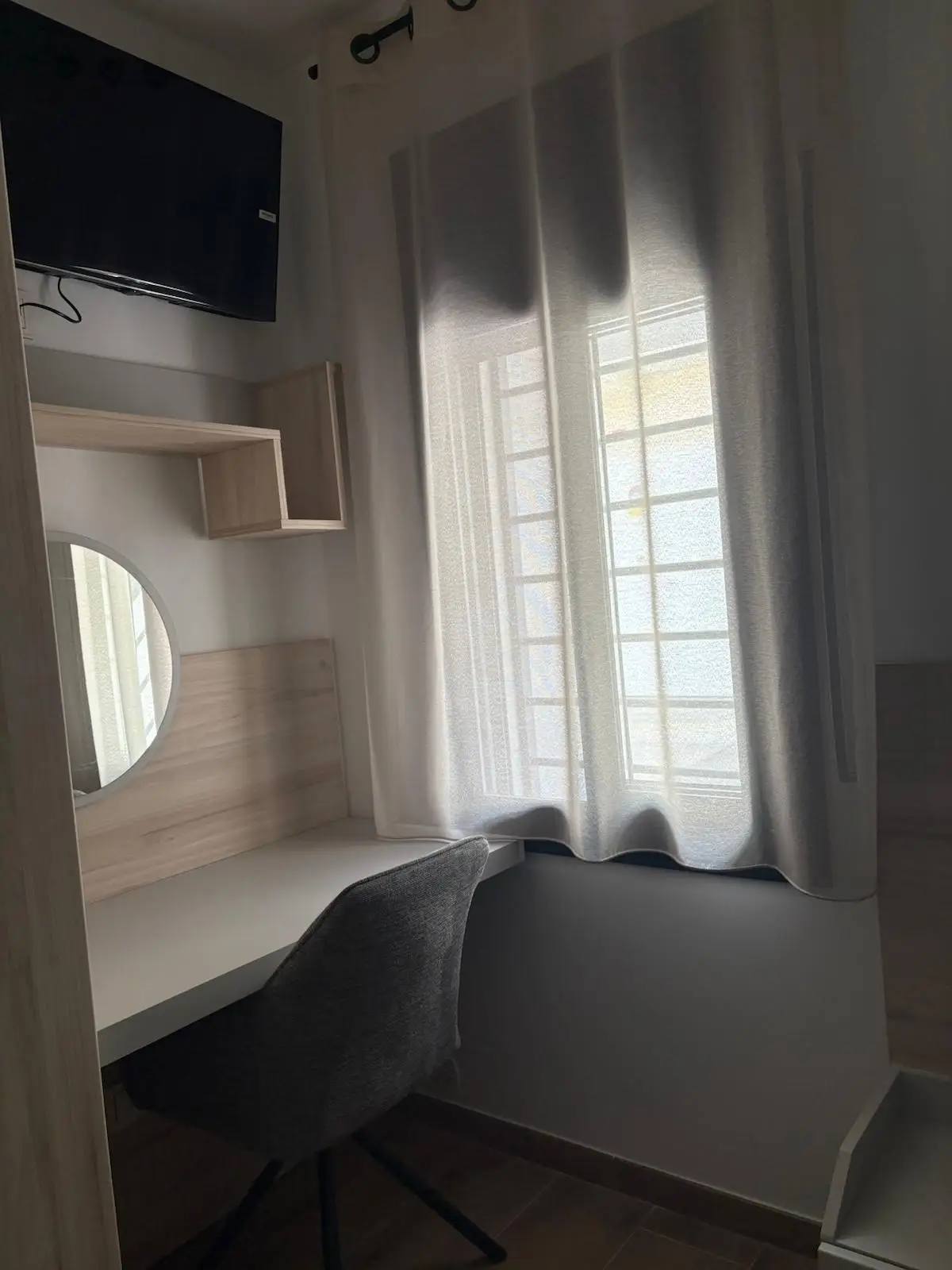 Reforma vivienda con escritorio de madera clara a medida y silla gris en Tarragona