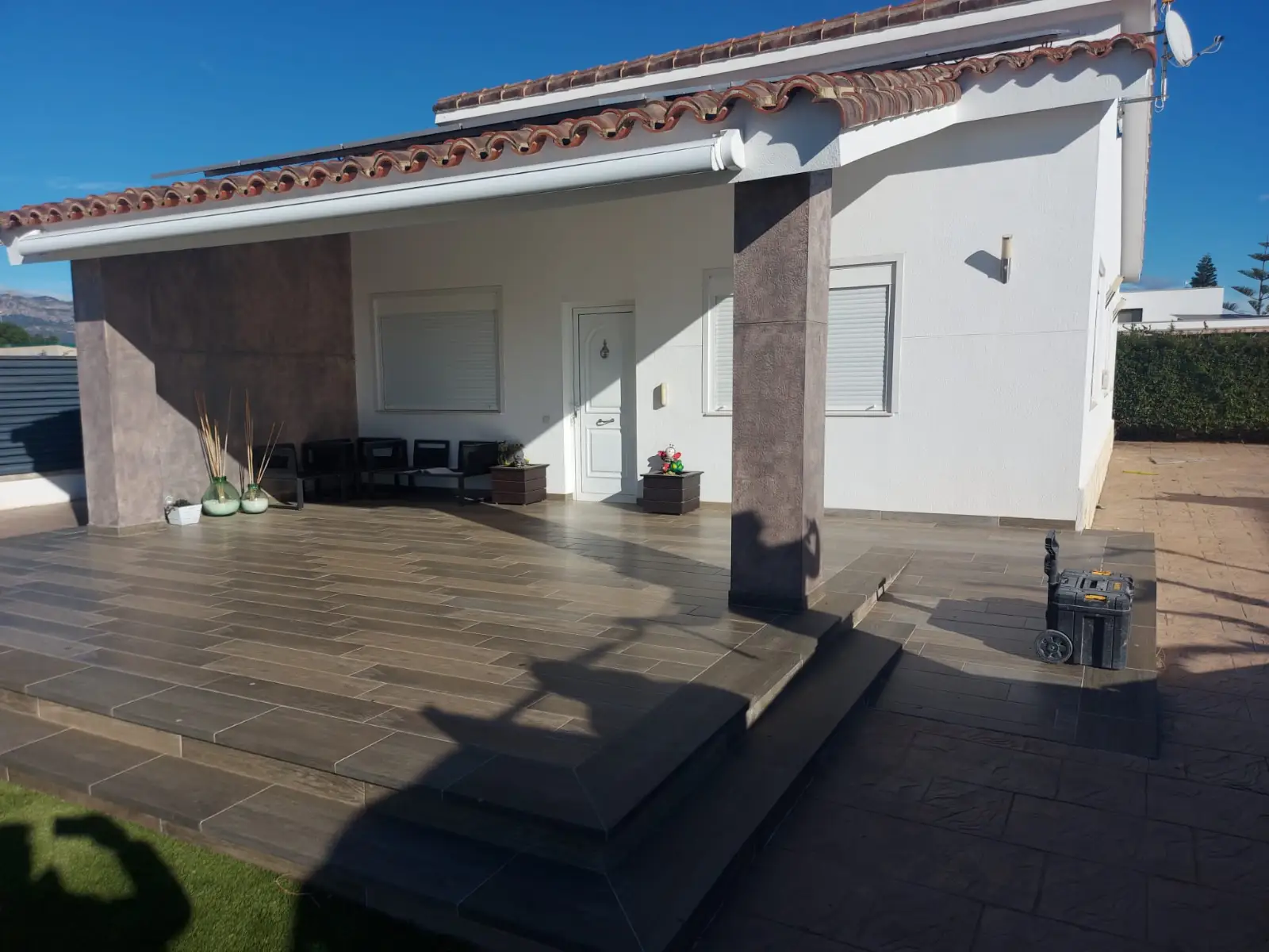 Reforma vivienda con porche exterior de suelo porcelánico imitación madera y columnas revestidas en Tarragona