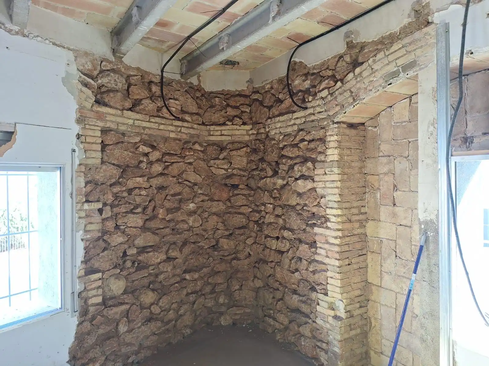 Rehabilitación de muro de piedra original y vigas de hormigón en una vivienda de Tarragona